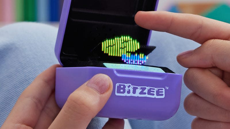 A user touching their Bitzee digital pet with their index finger.