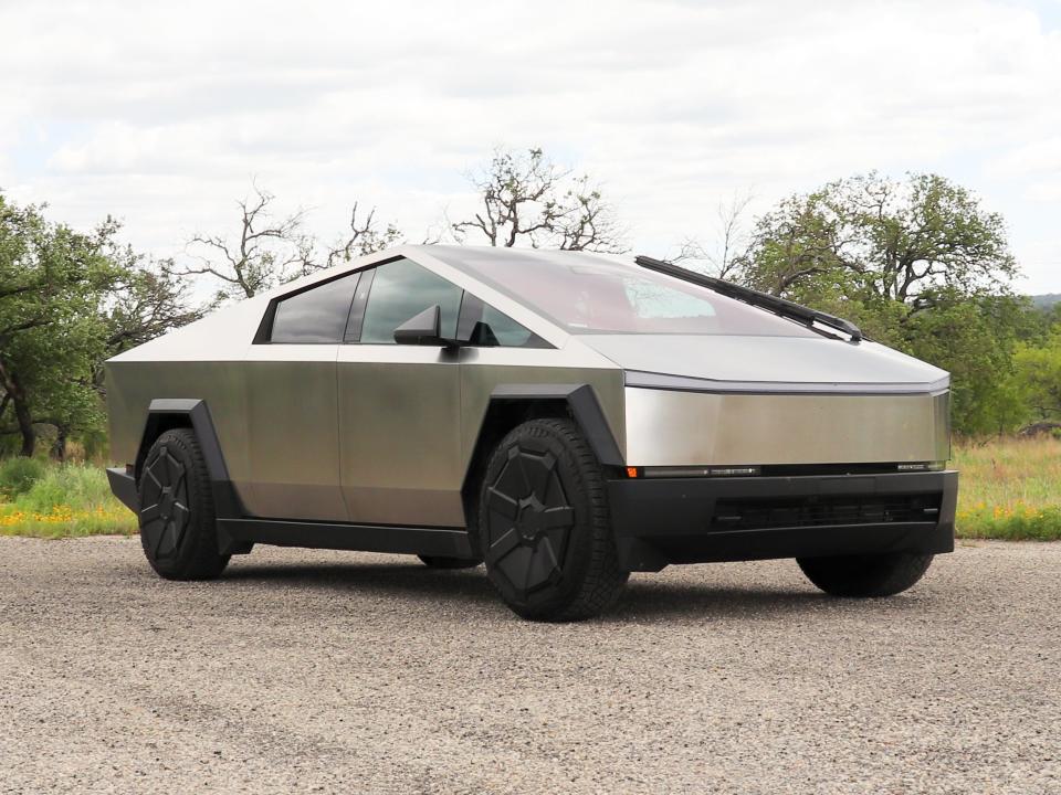 Tesla Cybertruck parked on a rural road with trees and grass in the background