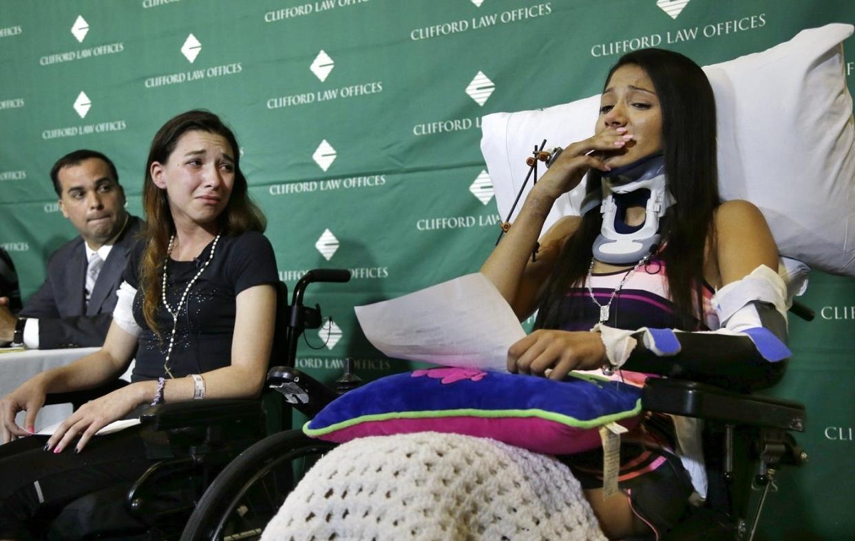 Circus acrobats Julissa Segrera, second from left, of the United States, and Dayana Costa, right, of Brazil, are tearful as Costa reads a statement to  the media at Spaulding Rehabilitation Hospital in Boston on June 17, 2014.