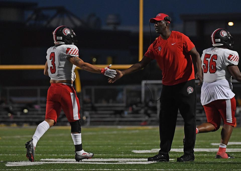 Isaiah Martinez #3 of the Aliquippa Quips is met by Head Coach Mike Warfield after a successful two point conversion in the first half during the game against the Montour Spartans at Thomas J. Birko Memorial Stadium on September 16, 2022 in McKees Rocks, Pennsylvania.