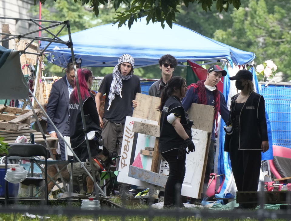 Protesters move signs as security clears the pro-Palestinian encampment at McGill University in Montreal, Wednesday, July 10, 2024. (Ryan Remiorz/The Canadian Press via AP)