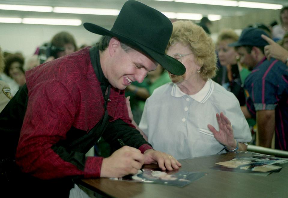 A fan gets a smile out of Garth Brooks as he signs his autograph for her at his booth during the 21st annual Fan Fair at the Tennessee State Fairgrounds June 9, 1992.