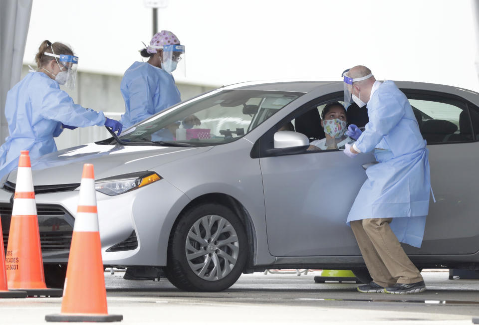 Healthcare workers gather information before conducting an antigen test, Wednesday, Aug. 5, 2020, at a COVID-19 testing site outside Hard Rock Stadium in Miami Gardens, Fla. State officials say Florida has surpassed 500,000 coronavirus cases. Meanwhile, testing is ramping up following a temporary shutdown of some sites because of Tropical Storm Isaias. Antigen testing reveals whether a person is currently infected with COVID-19. It differs from antibody testing because once the infection is gone, antigens won't be present. (AP Photo/Wilfredo Lee)