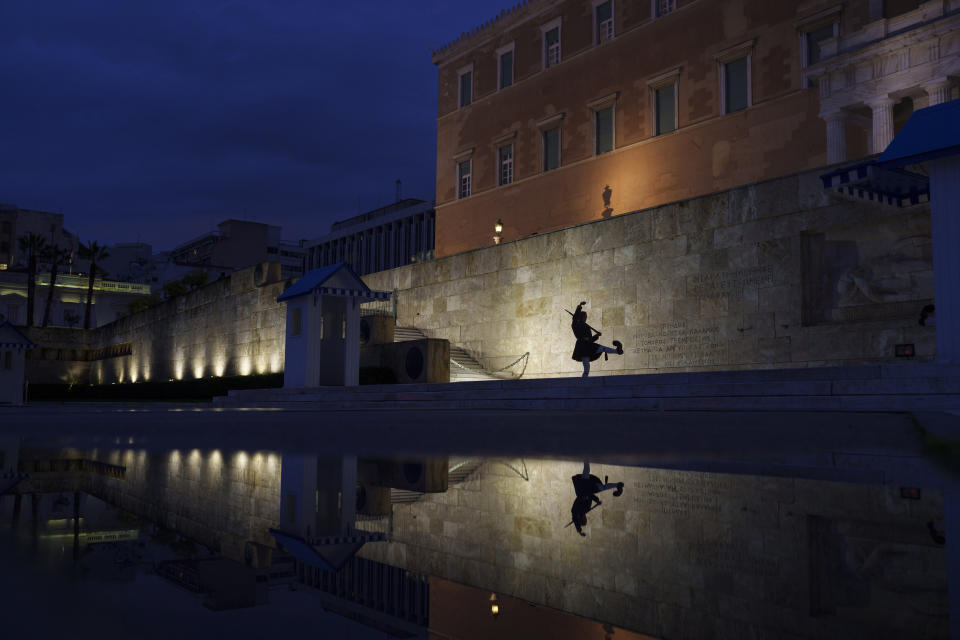 A Presidential guard is reflected in a puddle following a downpour in Athens, as he takes part in the changing of the guards ceremony, in front of the Greek Parliament, on Friday, March 1, 2024. (AP Photo/Petros Giannakouris)