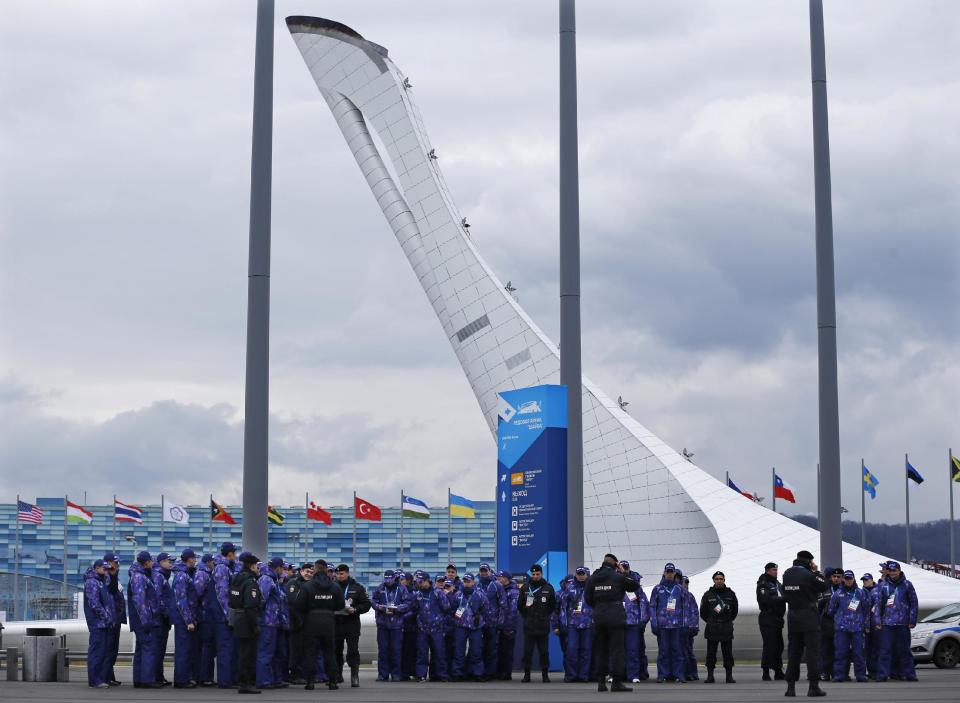 Russian security personal stand in the medal plaza near the Oylmpic flame as security measures are stepped in preparation for the 2014 Winter Olympics, Thursday, Jan. 30, 2014, in Sochi, Russia. (AP Photo/Pavel Golovkin)