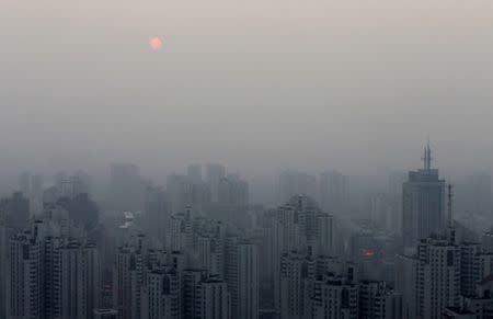 The sun sets above residential buildings on a hazy day in Beijing, September 20, 2014. REUTERS/Barry Huang/File Photo