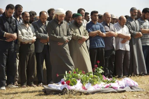 Syrian mourners pray over the body of a member of the Free Syrian Army during his funeral in the restive province of Homs, on June 22