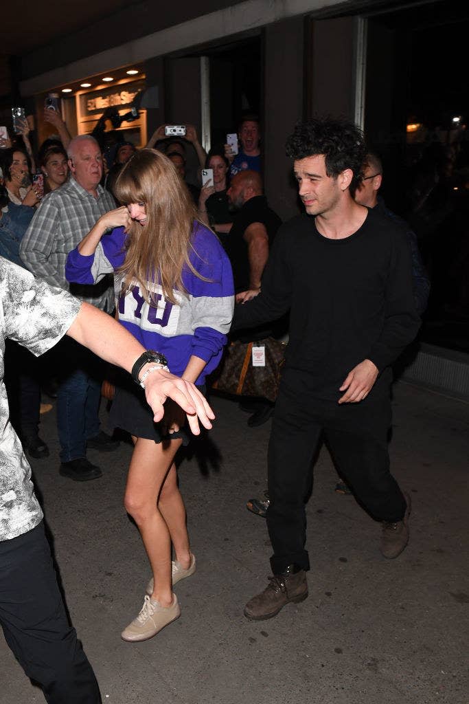 Closeup of Taylor Swift and Matty Healy walking out of a building