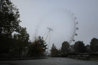 A squirrel runs in the foreground as the London Eye Ferris wheel stands newly closed to visitors and shrouded in fog, on the first day of Britain's second lockdown designed to save its health care system from being overwhelmed by people with coronavirus, in London, Thursday, Nov. 5, 2020. Britain joined large swathes of Europe in a coronavirus lockdown designed to save its health care system from being overwhelmed. Pubs, along with restaurants, hairdressers and shops selling non-essential items closed on Thursday until at least Dec. 2. (AP Photo/Matt Dunham)