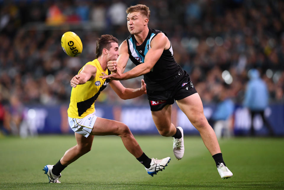 Ollie Wines (pictured right) handballs to a teammate during the round four AFL match between the Port Adelaide Power and the Richmond Tigers.