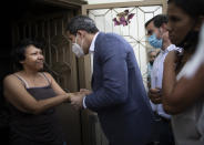 FILE - In this Dec. 10, 2020 file photo, Venezuelan opposition leader Juan Guaidó talks with a resident during a visit to La Lucha neighborhood of Caracas, Venezuela, amid the new coronavirus pandemic. The opposition led by Guaidó, who the U.S. recognizes as Venezuela’s rightful president, says President Nicolas Maduro can’t be trusted to distribute the vaccine in a country where the coronavirus pandemic has been used as a cover for human rights abuses. (AP Photo/Ariana Cubillos, File)