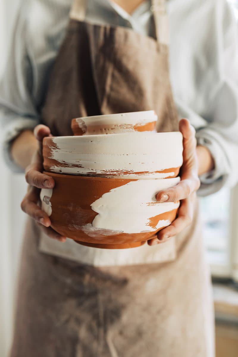 Female potter holding terracotta glazed clay bowls