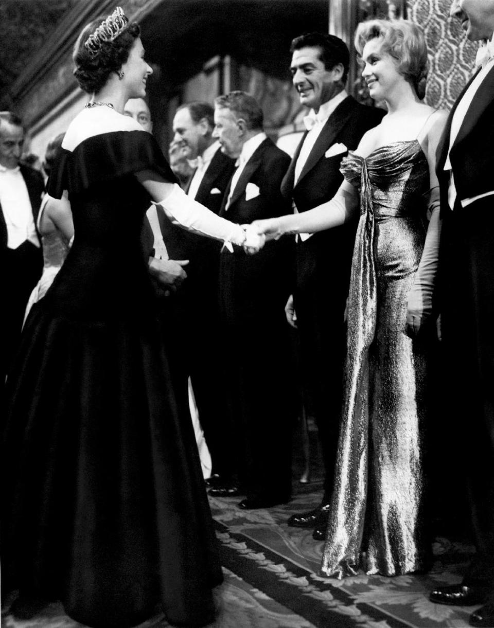 In this late October 1956 photo provided by courtesy Running Press, Marilyn Monroe, right, wearing a burnished gold lamé gown meets Queen Elizabeth in London. The photograph is included in a new 2012 book, "Marilyn in Fashion," published by Running Press. Monroe passed away a half-century ago this week, a murky death that remains one of Hollywood's most tantalizing mysteries. But look around: Her legend lives on, more vibrantly than ever. In a twist she surely would have appreciated, this 1950's bombshell has become a 21st-century pop culture phenom. (AP Photo/Courtesy Running Press)