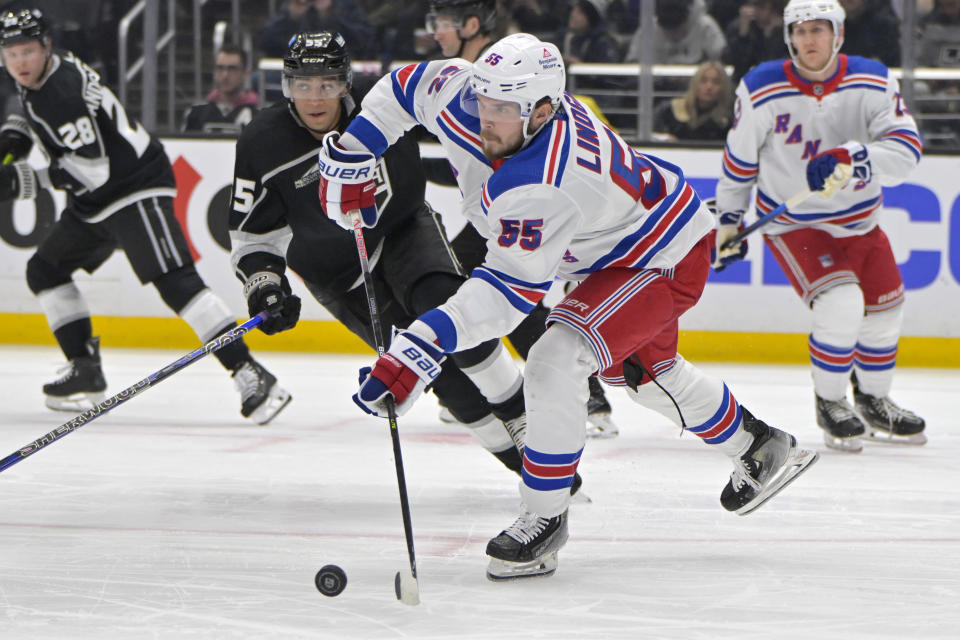 New York Rangers defenseman Ryan Lindgren, front, passes the puck in front of Los Angeles Kings right wing Quinton Byfield (55) during the second period of an NHL hockey game Saturday, Jan. 20, 2024, in Los Angeles. (AP Photo/Jayne-Kamin-Oncea)