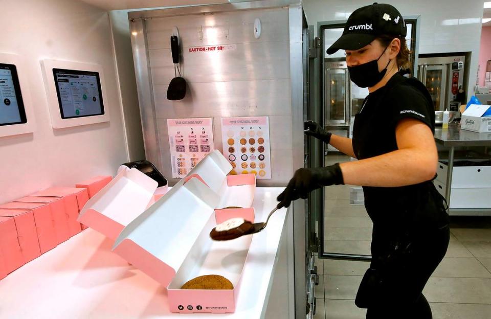 Brie Aho, an employee at the Crumbl Cookies location in Richland, fills boxes with fresh made cookies during a Tuesday afternoon rush of customers. The fresh and tasty treats are one idea for last-minute Christmas gifts.