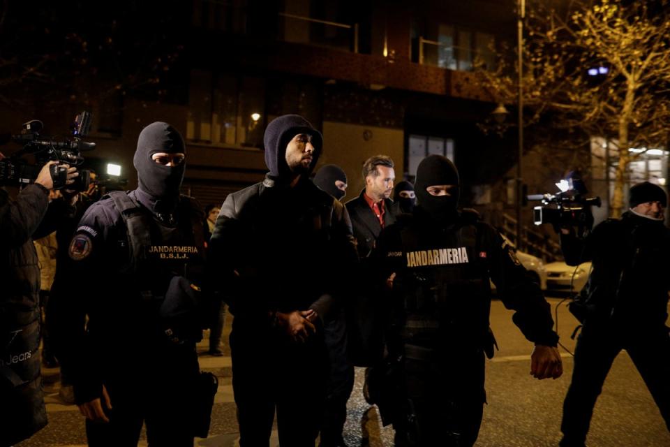 Andrew y Tristan Tate son escoltados por agentes de policía fuera de la sede de la Dirección de Investigación del Crimen Organizado y el Terrorismo en Bucarest (REUTERS)