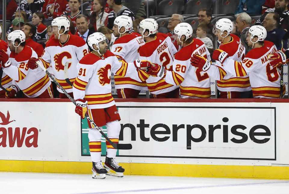 Calgary Flames center Nazem Kadri (91) celebrates with teammates after scoring a goal against the New Jersey Devils during the first period of an NHL hockey game, Tuesday, Nov. 8, 2022, in Newark, N.J. (AP Photo/Noah K. Murray)