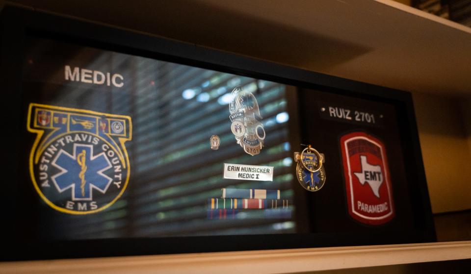 Erin Ruiz displays patches and awards from her EMS days in a shadow box at her home Wednesday. Ruiz worked as a paramedic for nine years, including while commuting from Waco because Austin wasn't affordable.