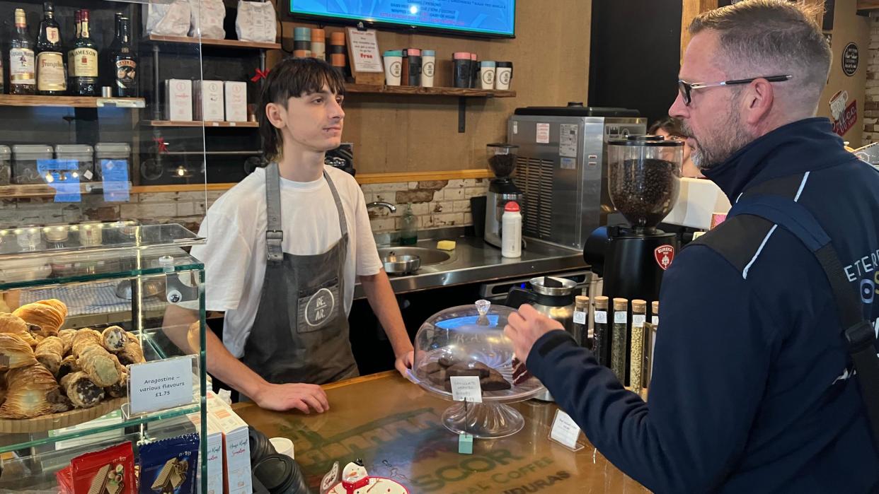 Terry speaking to a staff member- who is wearing a white shirt and a brown apron