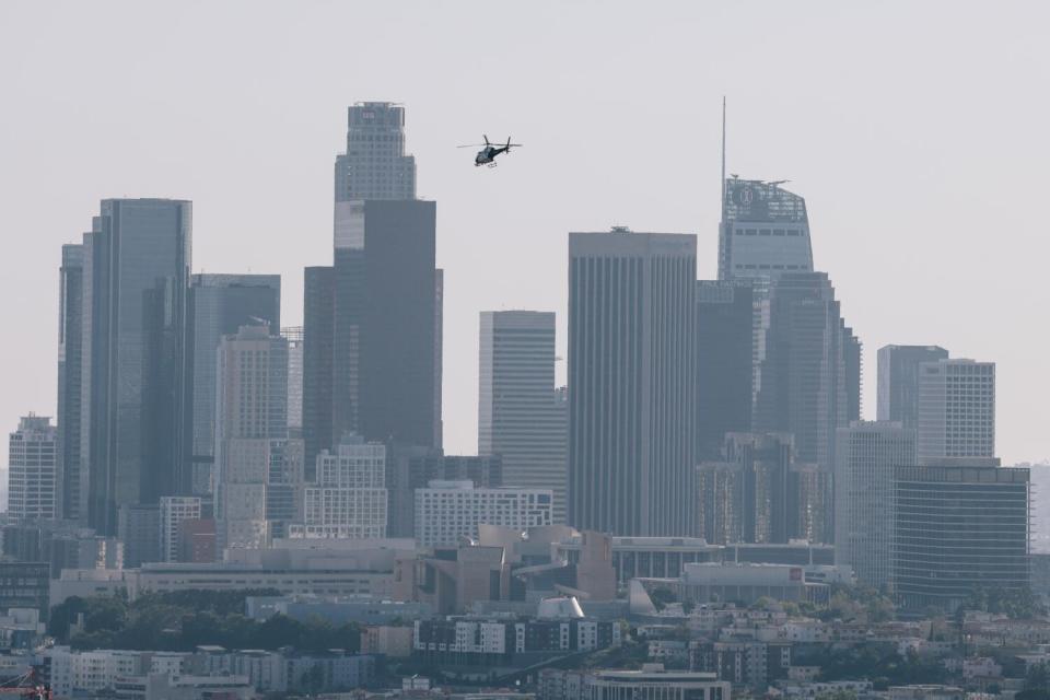 A helicopter hovers over a city skyine.