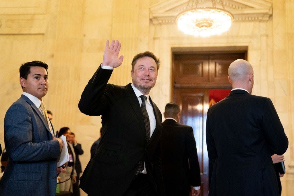 Elon Musk waves at the Capitol