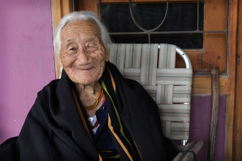 Kuou Kesiezie, a 108-year-old Angami Naga survivor of the Battle of Kohima fought between the Japanese and British Commonwealth forces in and around her village, smiles as she sits outside her daughter's house in Kohima, India, Thursday, Aug. 13, 2020. Kesiezie, who worked as a British army porter during World War II in 1944, vividly remembers sprinting down the Pulie Badze mountain area. She had hurried back homewards after dropping off a load of supplies when she realized she still had an ammunition belt strapped around her waist, she recalled with a chuckle. (AP Photo/Yirmiyan Arthur)