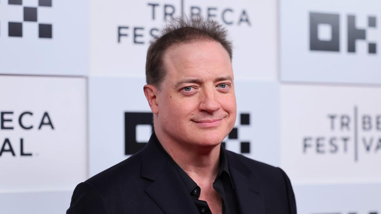 brendan fraser with a closed smile for a photo on a ilm premiere red carpet