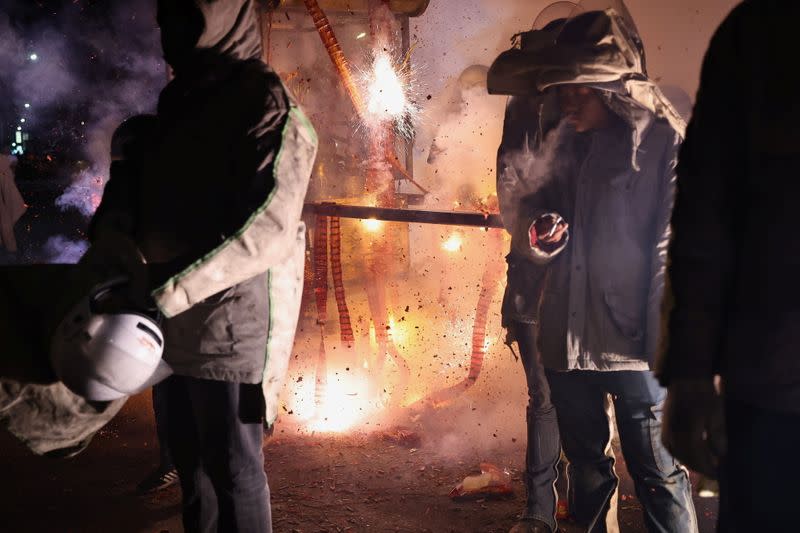 Participants wearing motorcycle helmets get sprayed with firecrackers, during the 'Beehive Firecrackers' festival at the Yanshui district in Tainan