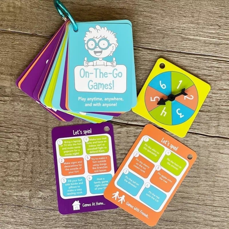 A set of On-The-Go Games cards and a clock hands spinner for travel-friendly interactive play