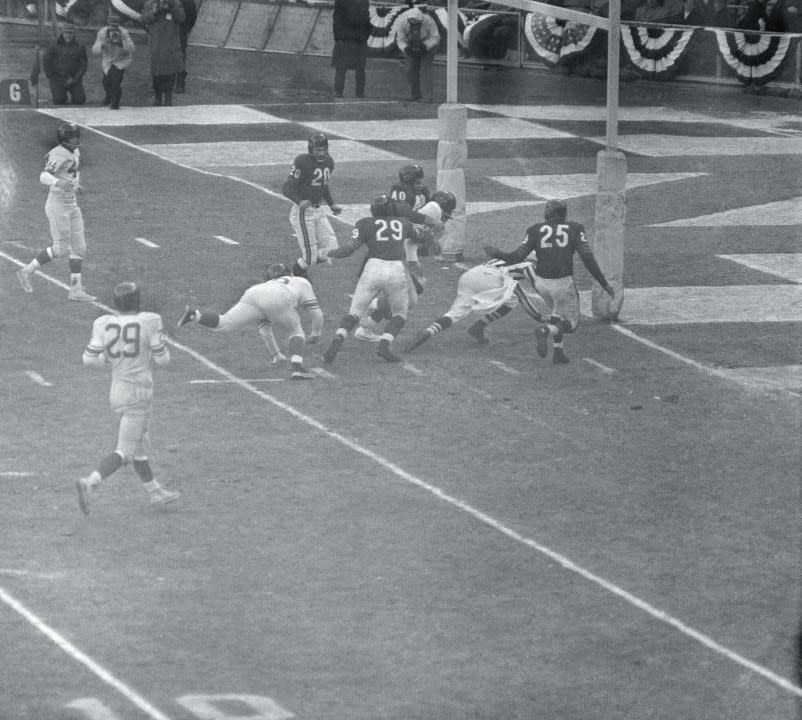 (Original Caption) Football official Sam Wilson (striped shirt) had a rough time of it in the early minutes of the New York Giants Chicago Bears Championship game at Yankee Stadium here December 30th, 1956. Wilson, the umpire at the game, couldn’t get out of the way fast enough when New York’s Mel Triplett broke up the middle to score the first Giant Touchdown. In top photo Wilson crashes to earth after being belted by Triplett (white jersey). Bear defenders Ray Smith (20) and J.C. Caroline (25) surround both Triplett and the hapless umpire as New York’s Jack Stroud sprawls at left. In bottom photo, Wilson is completely buried under the pileup as Triplett crosses the goal line. Back Judge George Rennix (right) signals the score, as Ray Smith bounces back after slamming into the goal post in a vain try fro Triplett. The Giants smothered the Bears, 47-7. (Getty via Bettmann/Contributor)
