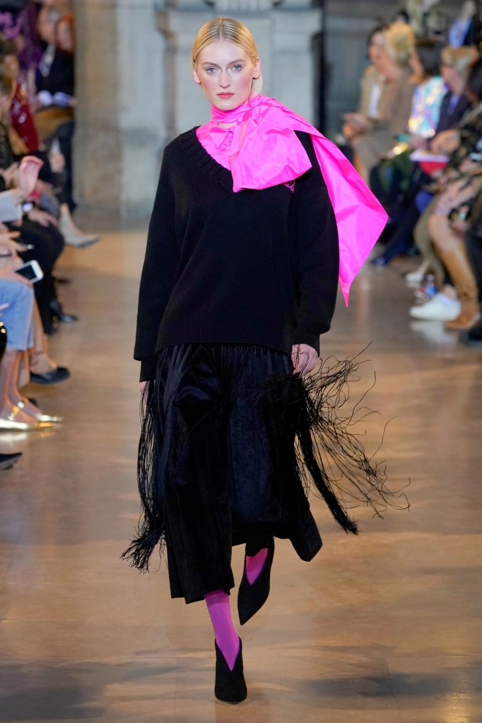 <p>Pinke Details sind auch an diesem Outfit entscheidend. Die Tights und das Seidentuch in Neonpink geben dem Style aus Oversize-Pullover und Culottes mit Fransen einen klassischen und gleichzeitig modernen Touch. (Bild: Talbot Runhof) </p>