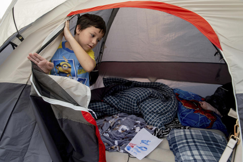 Adrian Childress, 7, opens a tent flap at the the Green Valley Community Church evacuation shelter on Thursday, Aug. 19, 2021, in Placerville, Calif., after his family fled the Caldor Fire. (AP Photo/Ethan Swope)