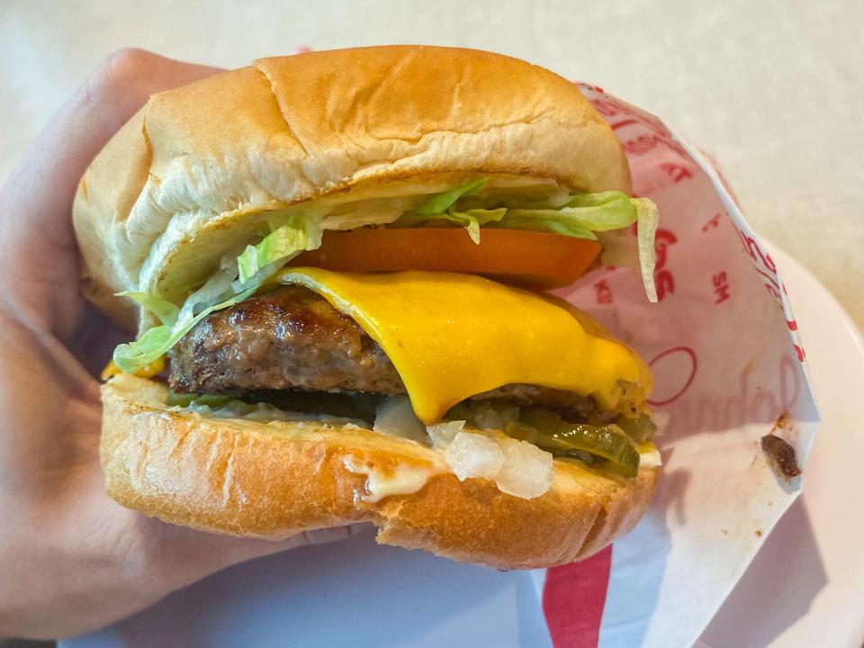 A close up of a hand holding a burger at Johnny Rockets