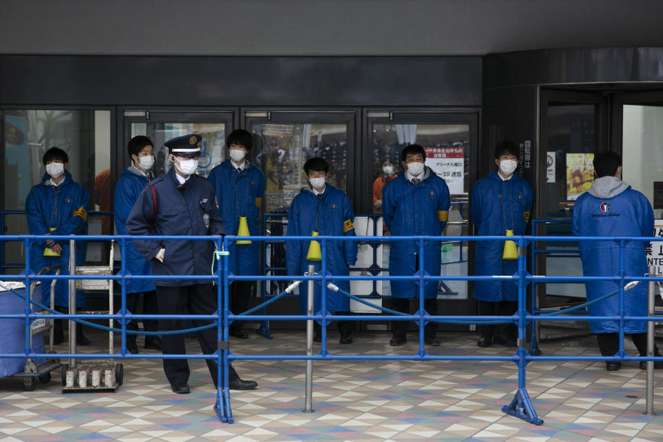 Ushers wear protective face masks before the start of a concert by Japanese girl group Perfume outside Tokyo Dome in Tokyo, Tuesday, Feb. 25, 2020. Japanese health officials and experts on a government panel are acknowledging that the quarantine of the virus-hit cruise ship Diamond Princess was not perfect. (AP Photo/Jae C. Hong)