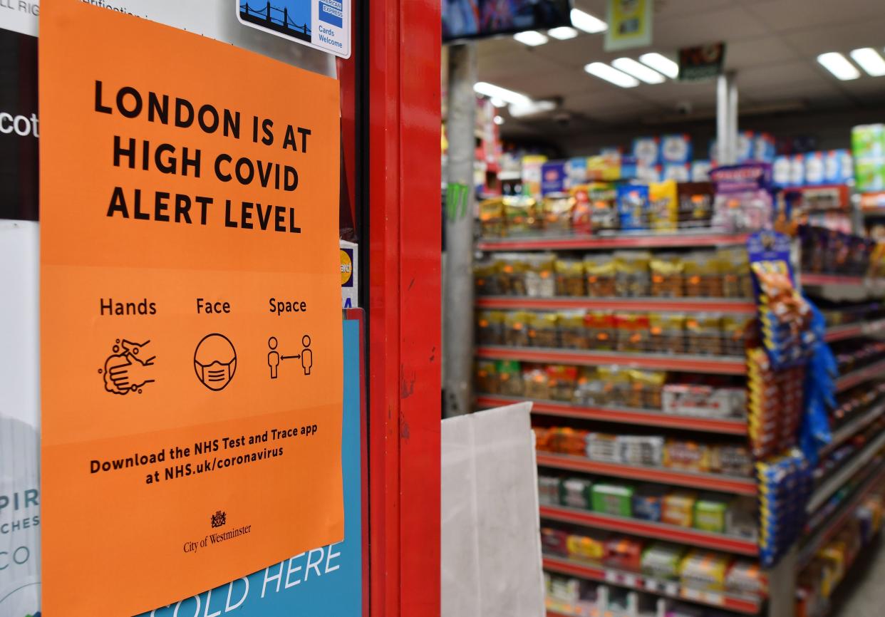 A convenience store displays a sign informing customers that London is at a "High" Covid alert level in the Soho district of London on October 18, 2020, as further restrictions come into force to combat the rising numbers of novel coronavirus covid-19 cases. - Britain's pub industry is bearing the brunt of new restrictions introduced to combat rising coronavirus infection rates. Soaring rates in north-west England have forced stringent restrictions, with pubs only allowed to serve alcohol as part of sit-down meals. (Photo by JUSTIN TALLIS / AFP) (Photo by JUSTIN TALLIS/AFP via Getty Images)