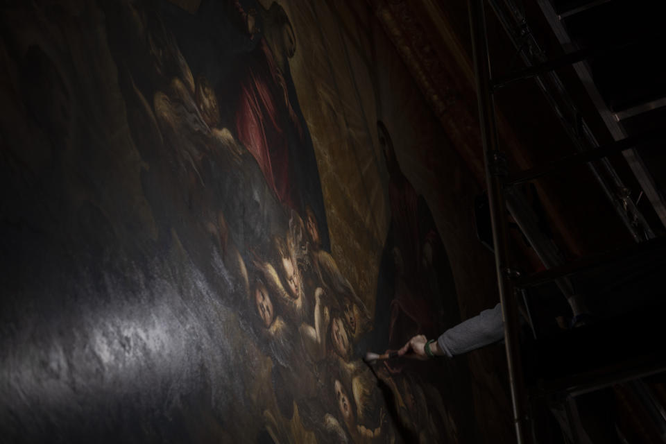 Restorer Alberto Marcon inspects the 7,45x24,65-meter oil on canvas 'Il Paradiso' completed in 1592 by Venetian painters Jacopo Robusti, also known as Tintoretto, and his son Domenico in the Maggior Consiglio Hall inside Palazzo Ducale in Venice, northern Italy, Wednesday, Dec. 6, 2022. The Doge's Palace, the heart of the political life of the Venetian Republic for centuries, is undergoing a major reconnaissance of its conservation status by the Fondazione Musei Civici of the municipality of Venice that includes the urgent restoration of its paintings and infrastructures, which is expected to be completed in the summer of 2023. (AP Photo/Domenico Stinellis)