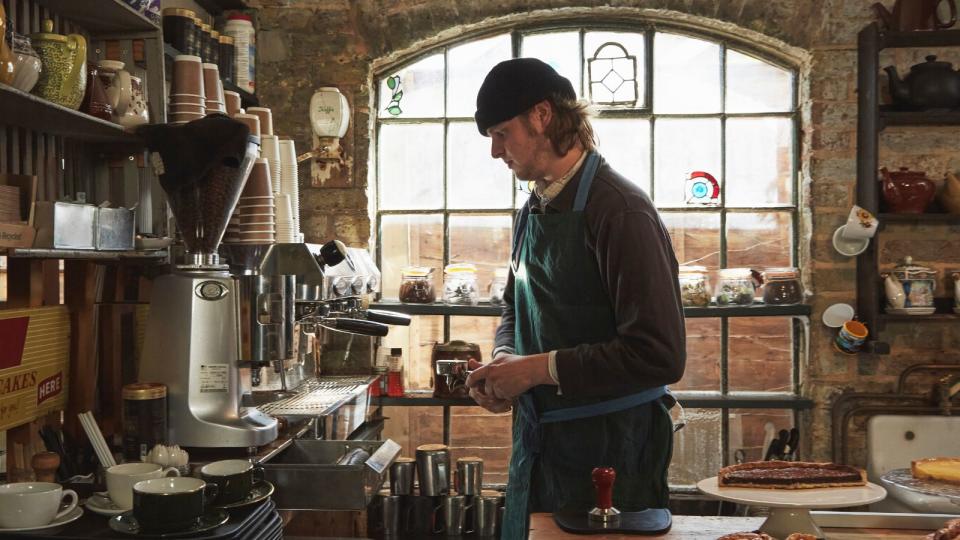 A barista behind a bar making an espresso