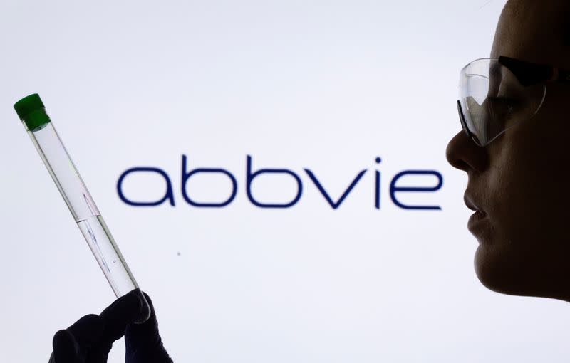 FILE PHOTO: A woman holds a test tube in front of displayed Abbvie logo in this illustration