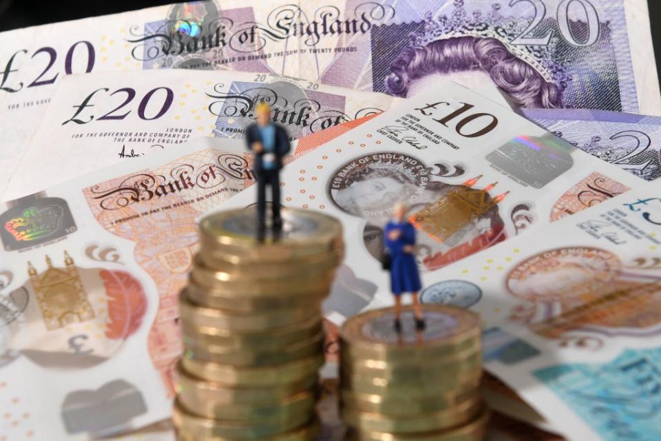 Models of a man and woman stand on a pile of coins and bank notes (Joe Giddens/PA) (PA Archive)