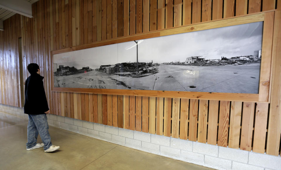 In this photo taken April, 18, 2014, a large photo of tornado damage hangs in a hallway of the rebuilt high school in Greensburg, Kan. Seven years after an EF-5 tornado destroyed most of the community of 1,500, Greensburg's population is around 850 residents. (AP Photo/Charlie Rieel)