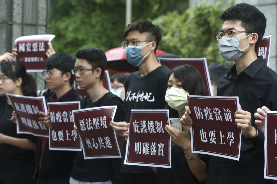 Hong Kong students and Taiwanese supporters hold slogans reading: "Evil law under the pressure of the border, Work hand in hand " and ''The asylum mechanism is clearly in place'' during a protest against Beijing's national security legislation in Taipei, Taiwan, Thursday, May 28, 2020. (AP Photo/Chiang Ying-ying)