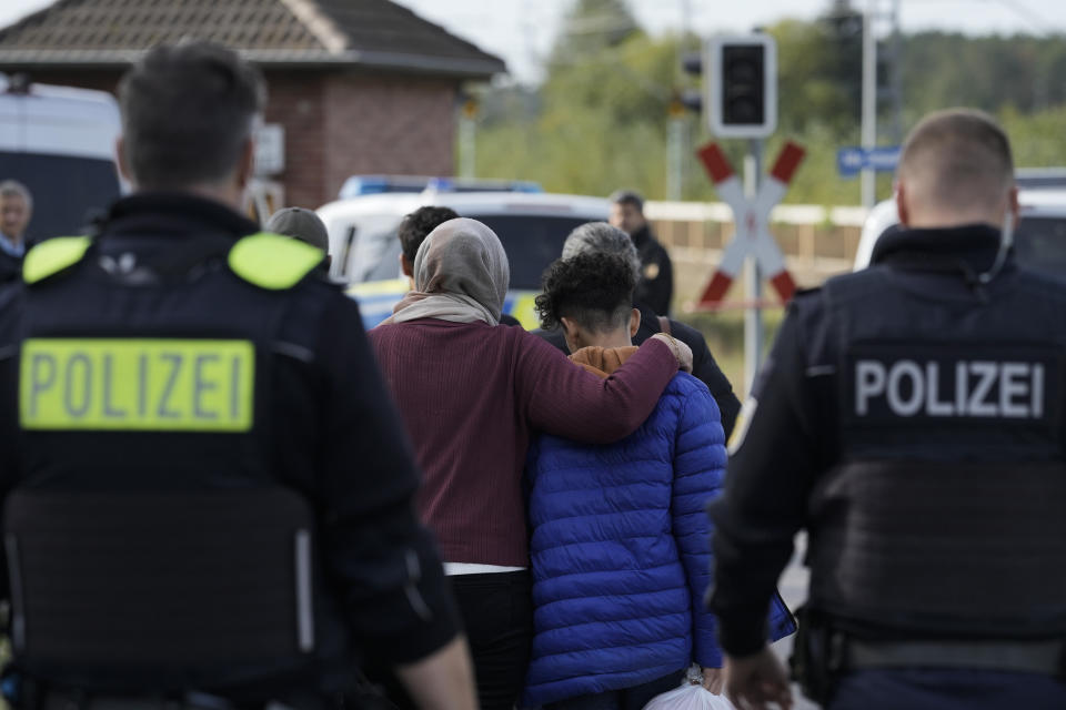 A mother embraces her son after they illegally crossed the border from Poland into Germany and tracked down by a Federal Police patrol in a forest near Forst southeast of Berlin, Germany, Wednesday, Oct. 11, 2023. (AP Photo/Markus Schreiber)