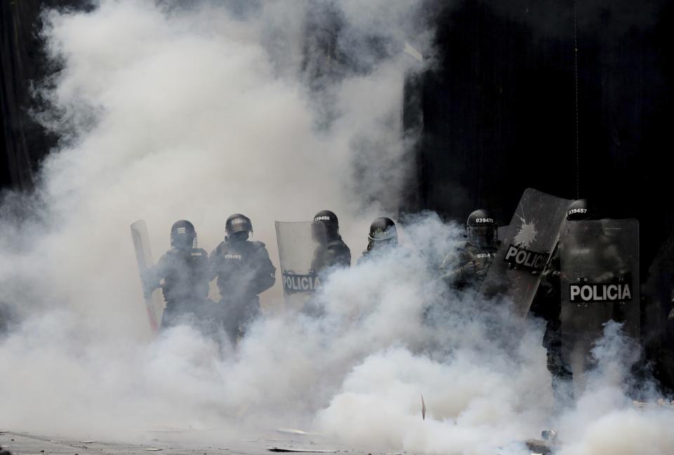 Police are engulfed by a cloud of tear gas after dispersing anti-government protesters at Bolivar square in downtown Bogota, Colombia, Thursday, Nov. 21, 2019. Colombia's main union groups and student activists called for a strike to protest the economic policies of Colombian President Ivan Duque government and a long list of grievances. (AP Photo/Fernando Vergara)