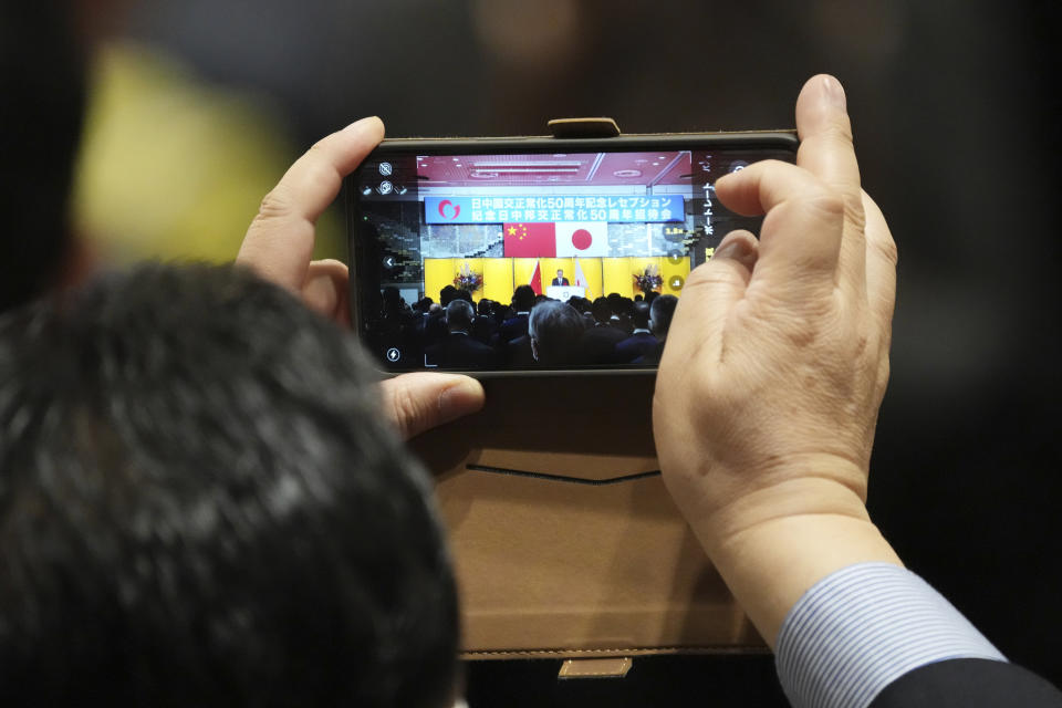 One of guests films a speech with a mobile phone during a reception to mark the 50th anniversary of Japan-China diplomatic relations Thursday, Sept. 29, 2022, in Tokyo. (AP Photo/Eugene Hoshiko)