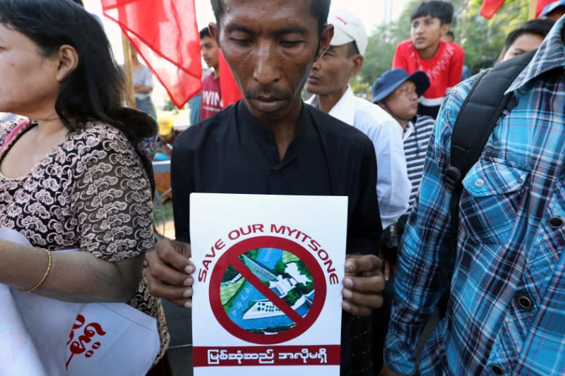 A protester holds a flyer against Myitsone hydropower dam during the last day of Chinese President Xi Jinping's visit in Yangon