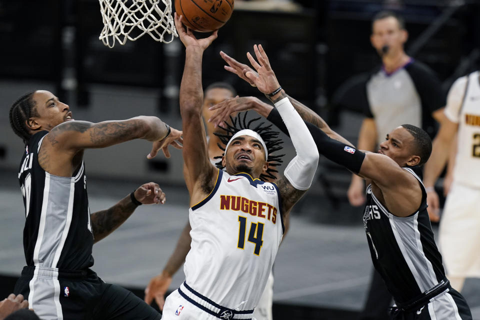 Denver Nuggets guard Gary Harris (14) drives to the basket between San Antonio Spurs forward DeMar DeRozan, left, and guard Dejounte Murray during the second half of an NBA basketball game in San Antonio, Friday, Jan. 29, 2021. (AP Photo/Eric Gay)