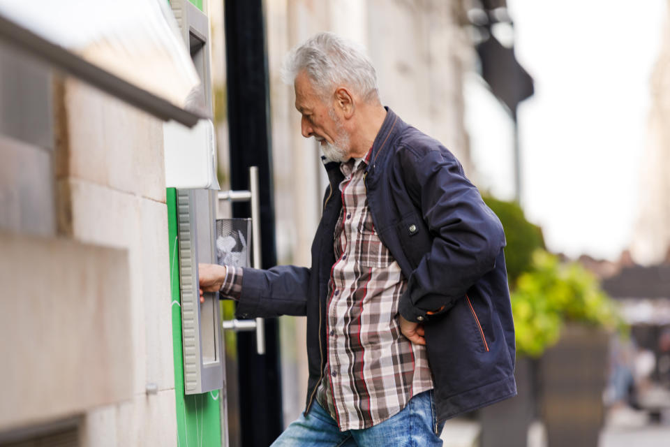 Bearded Senior Man is Standing in the City Street and Using ATM.