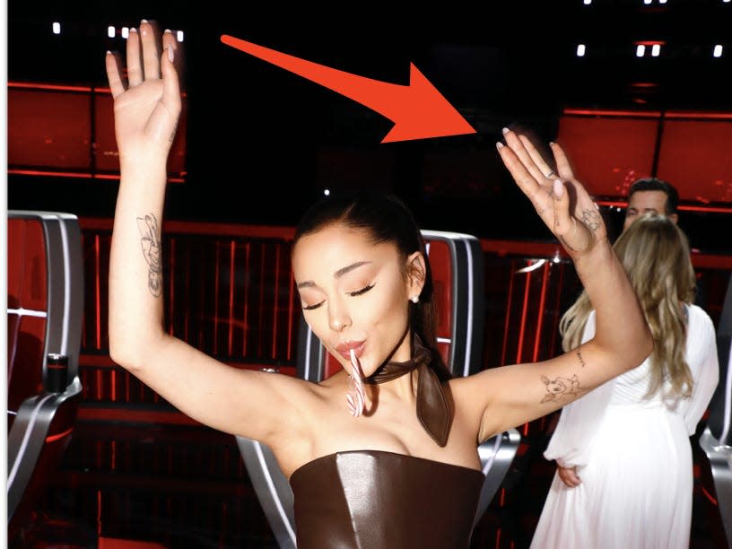 Ariana Grande with an arrow pointing to her finger tattoo.