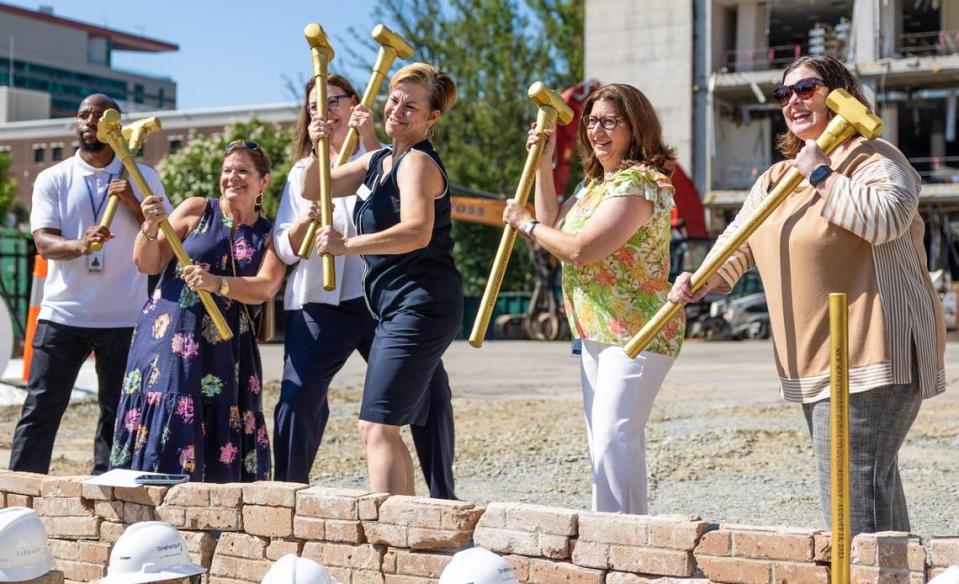 Members of the Charlotte Mecklenburg Library Foundation get a groundbreaking demolition photo in Uptown Charlotte on Tuesday, August 15, 2023. The Library has been slated for demolition for years as the branch makes way for a new, state of the art facility. The builders expect to have the old building demolished by the end of the year and they are planning on completing the new library by 2026.