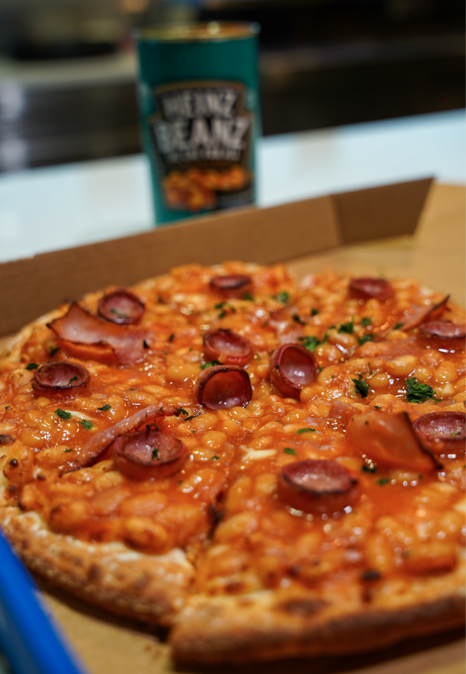 close up of a baked beans pizza with a can of baked beans in the background 